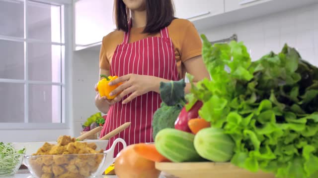 年轻的亚洲妇女在厨房做饭。视频素材