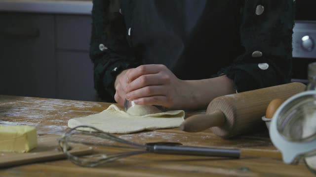 在舒适的厨房里，漂亮的女人在木桌上准备馅饼。家务和爱好概念。视频素材