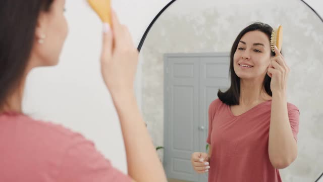 一个漂亮女人在浴室里梳着漂亮的黑发的慢镜头视频素材