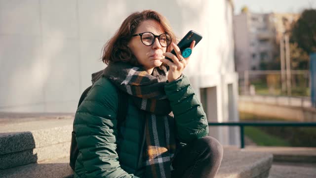 一个戴眼镜的年轻女子在用手机录语音信息视频素材