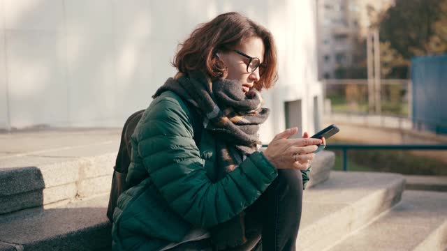 一个戴眼镜的年轻女子在用手机录语音信息视频素材