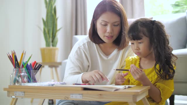 妈妈在家里的客厅教小女孩画画视频素材