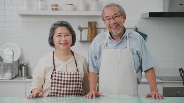 夫妇老亚洲长者幸福生活在家庭厨房。爷爷抱着奶奶幸福地笑着一起享受退休生活。老年人的家庭关系和活动概念。视频素材