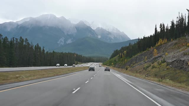 在班夫国家公园的高速公路和岩山上开车的公路旅行视频素材