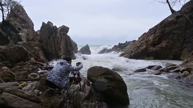 人们在海岸线上拍了一张照片，暴风雨中的巨浪击中了石头视频素材