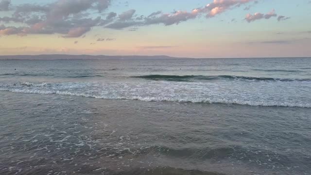 鸟瞰图的海面与蓝色的海浪下日落的天空。视频素材