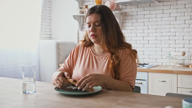 饮食失调。胖女人大吃特吃披萨，坐在家里的厨房里。视频素材