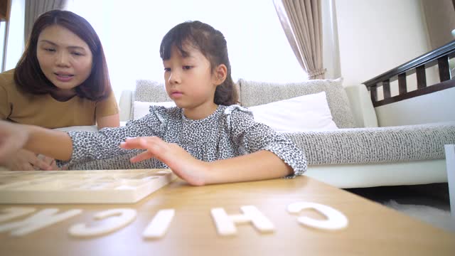 小女孩在家里的客厅里玩和学习字母视频素材