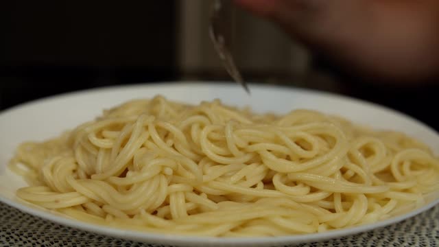 一个男人用叉子吃着白色盘子里的意大利面，特写视频素材