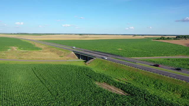 沥青公路高速公路穿过绿色农田与驾驶汽车空中视频素材