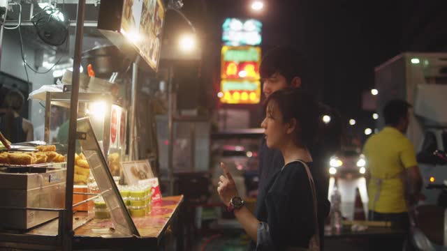 一对亚洲情侣在街头小吃上约会。视频素材