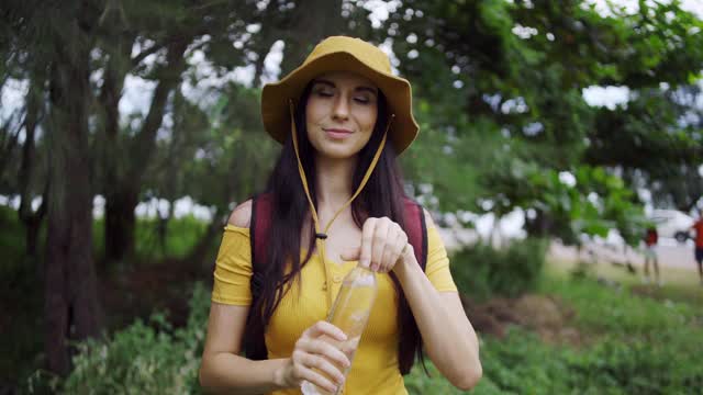 女性白种人喝水后旅行的野生冒险在森林假日。视频素材