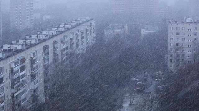 城市下雪了。冬天的雪。暴风雪的背景是城市里的汽车和建筑物。视频素材