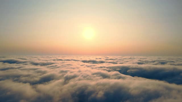 在日落时飞过云层。太阳从雾中升起。雾上橙色的夕阳。视频素材