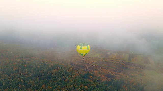 高空鸟瞰图气球飞行在一个多云多雾的日子。阴沉的冬日气球被风吹走了。视频素材