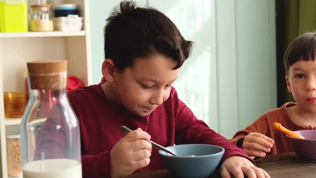 可爱的孩子们早餐吃玉米片和牛奶。视频素材