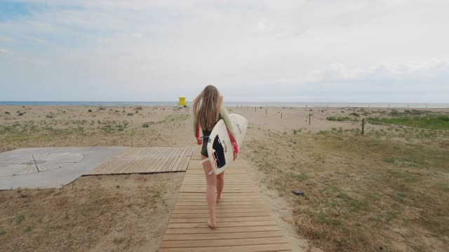 年轻漂亮的女人在海滩上玩冲浪板视频素材