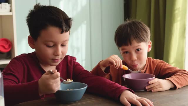 可爱的孩子们早餐吃玉米片和牛奶。视频素材