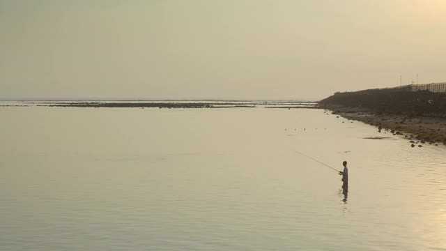 黄色的夕阳下，亚洲巴厘渔民在机场跑道附近的海上捕鱼视频素材