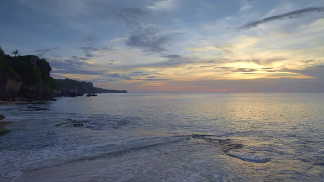 热带海滩与大波浪和悬崖在日落与人视频素材