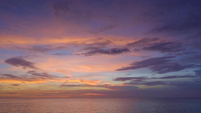 美丽的日落与紫色和红色的天空和小海浪的海洋视频素材