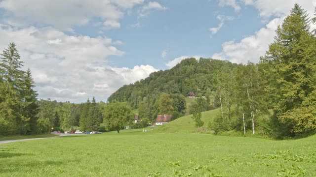 时间流逝云朵掠过小山。典型的瑞士住宅位于长满草的山谷中。广州的火车。视频素材