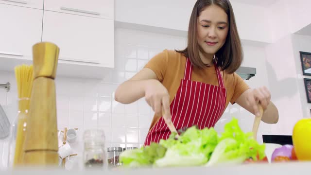 年轻的亚洲妇女在厨房做饭。视频素材