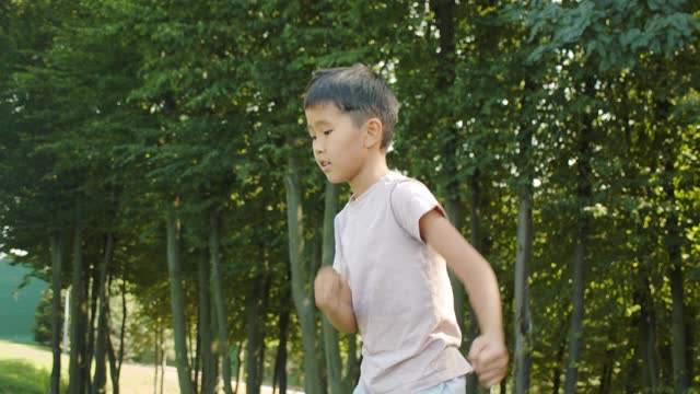 这个亚洲小男孩在公园里训练，功夫，空手道，踢腿，壁上搏击，背景是阳光明媚的夏日运动视频素材