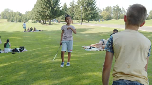 两个小男孩打羽毛球，公园，夏天，童年，跨国，亚洲和高加索视频下载