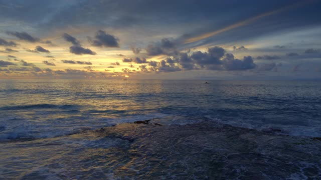 在美丽的日落与船剪影在深蓝色的海洋热带海滩上的高潮波浪视频素材