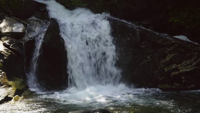 山瀑布之间的岩石和树木视频素材