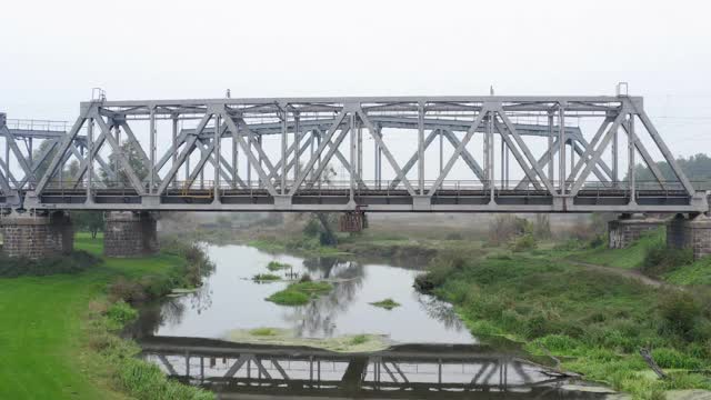 电气化火车通过横跨这条河的铁路桥。视频素材