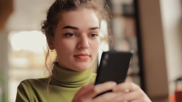 年轻女子用电话在咖啡馆喝茶视频素材