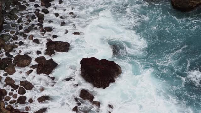 蓝绿色的海浪撞击着海岸附近的火山岩。视频素材