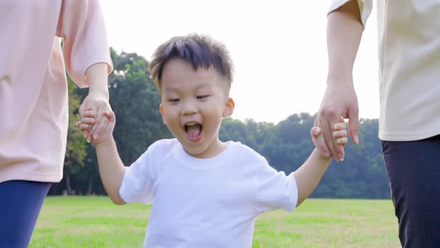 快乐的小男孩和父母在公园里跑步视频素材