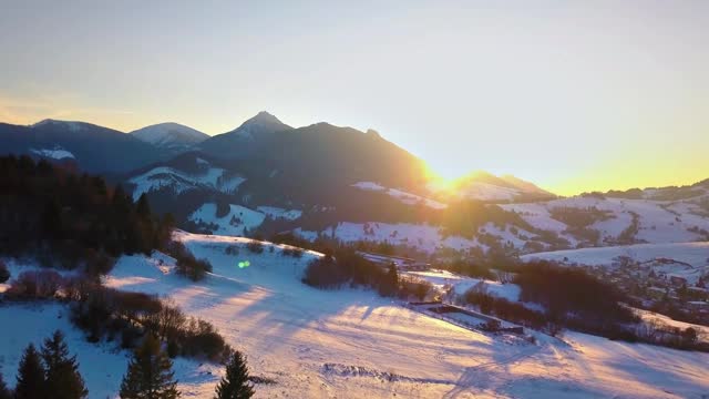 鸟瞰图的色彩缤纷的冬季日落农村在雪山的自然景观视频素材