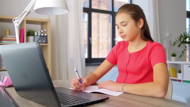 十几岁的学生女孩在家里写笔记本视频素材