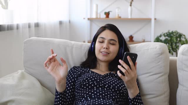 一名年轻的亚洲越南女子戴着耳机听音乐。视频素材