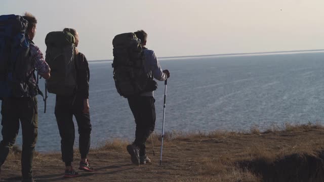 四个徒步旅行者在海边的山上散步视频素材