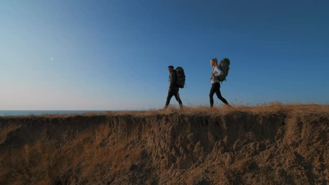 在夕阳的背景下，这对夫妇在山上散步视频素材