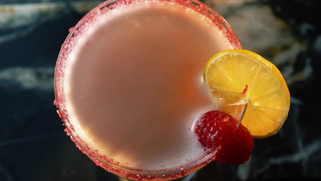 特写顶部的镜头，一个清爽的鸡尾酒在酒吧和一个女性的手装饰水晶玻璃与一朵花视频素材