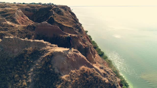 旅行者站在山崖上，背景是海景视频素材