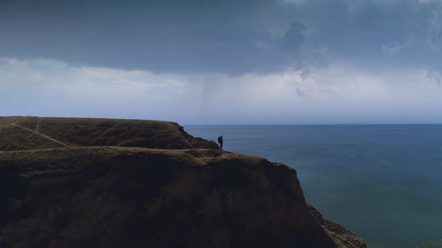 背双肩包的男人站在山顶上美丽的海景上视频素材