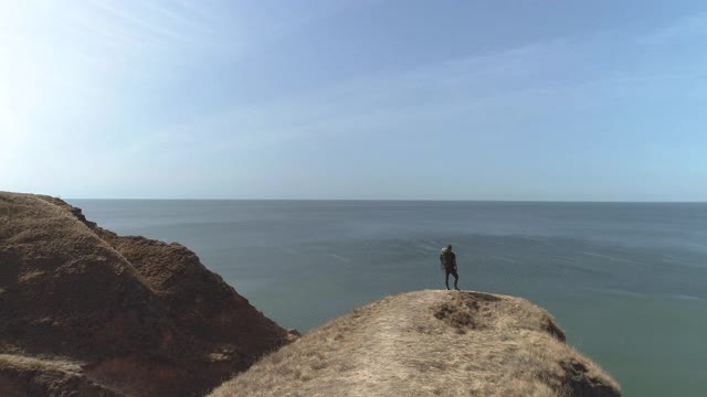 那个背着背包的人站在山边美丽的海景上视频素材