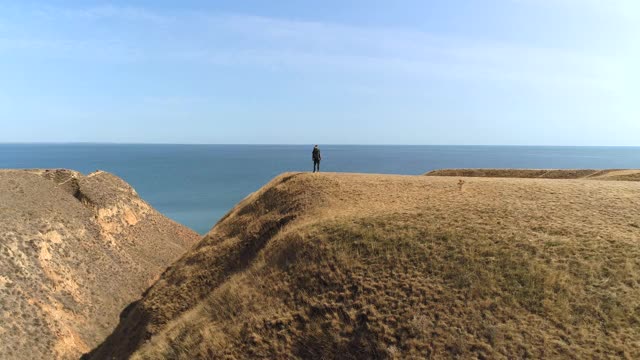 背背包的人背对着大海站在山顶上视频素材