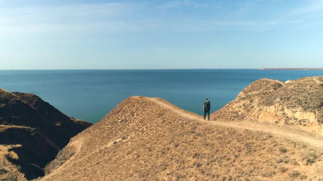 背包的游客在美丽的海景上行走在山脉上视频素材