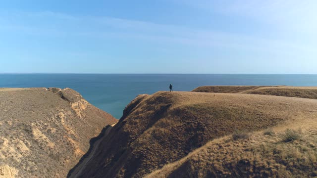 那个背着背包的人站在山顶上，背对着海景视频素材