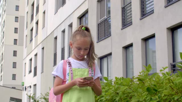 少女看手机在城市行走在夏天。关注青少年女孩行走在城市街道上使用智能手机在夏季城市。视频素材