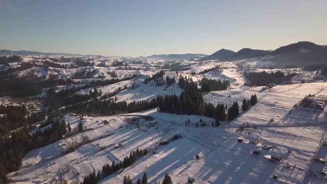 鸟瞰图上的小村庄，在冬天被雪覆盖的山丘上散落着房屋，裸露的喀尔巴阡山脉在乌克兰。视频素材