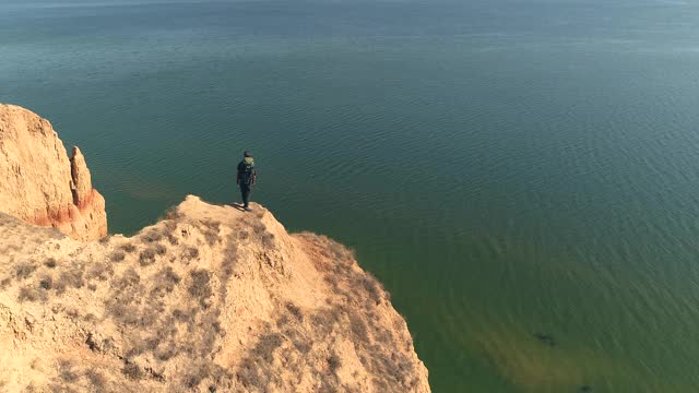 背背包的旅行者站在山顶背对着大海视频素材